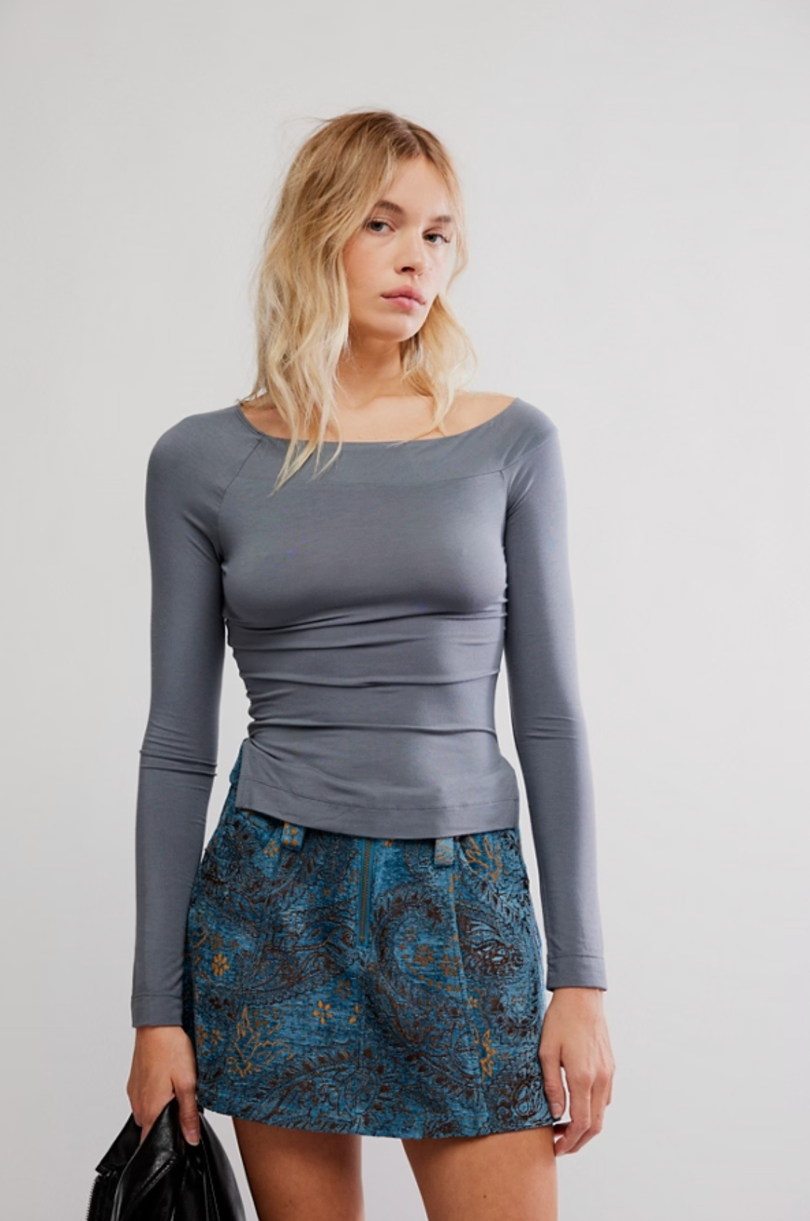 Woman wearing slate gray fitted wide-neck long sleeve top with blue jacquard mini skirt