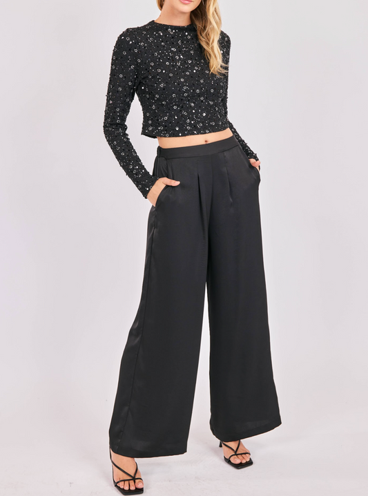 Woman wearing black satin wide-leg pants paired with a matching strapless top.