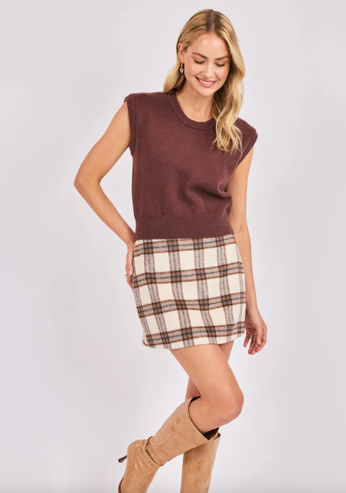 Woman wearing a brown sleeveless top and plaid skirt on a white background