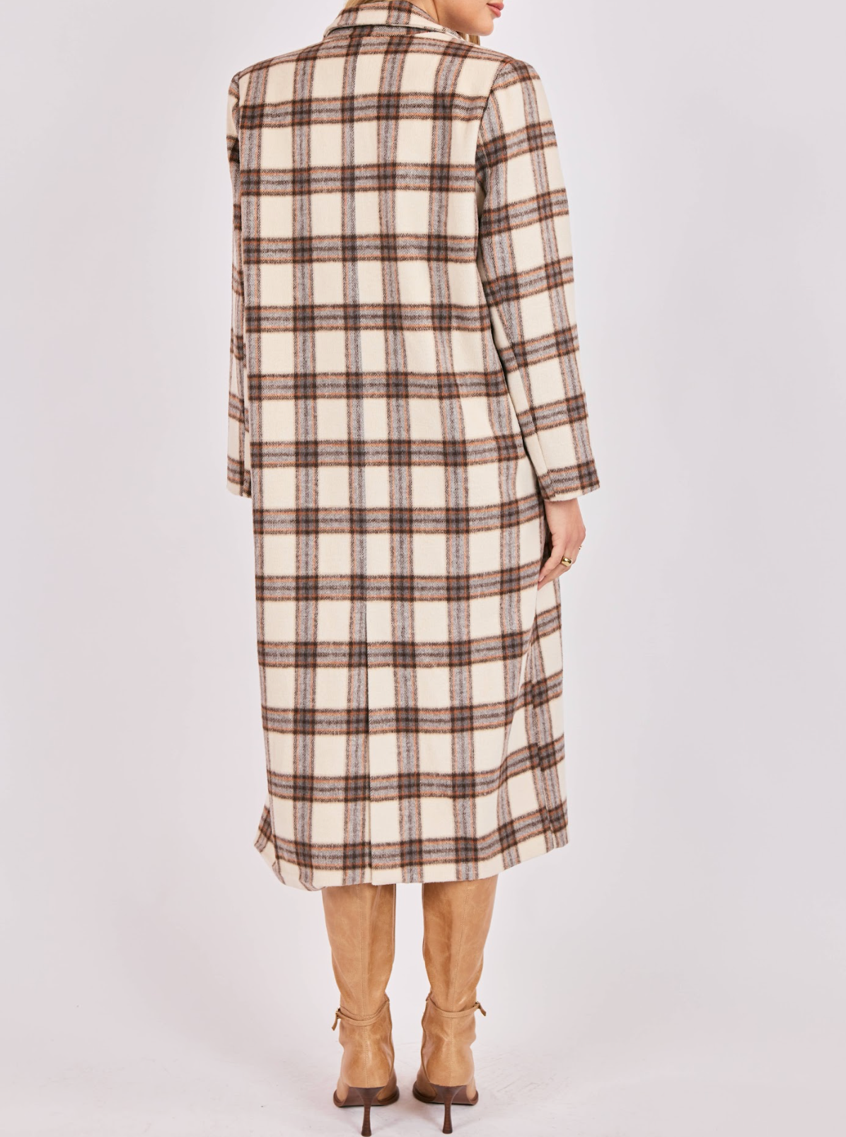 Person wearing a long plaid coat on a plain background