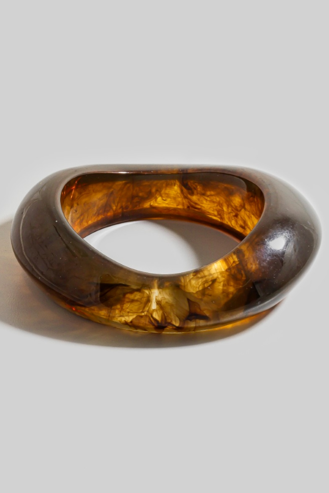 Thick amber resin bangle with irregular sculpted shape and translucent finish