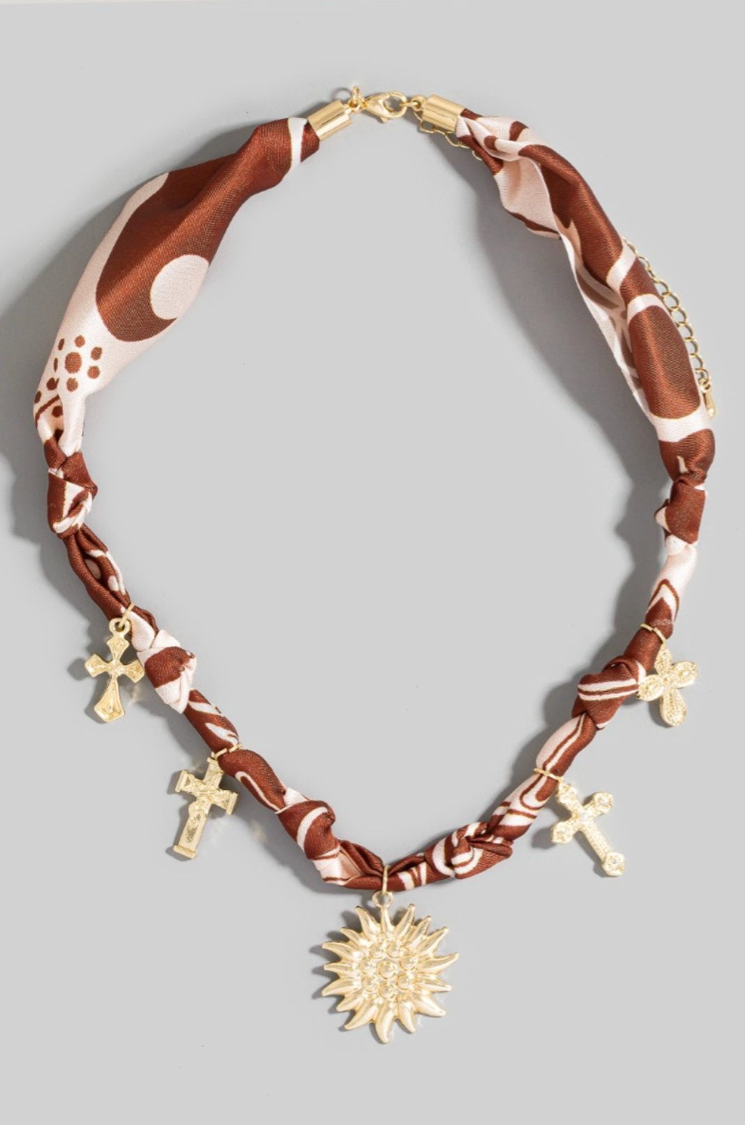 Gold sun and cross charm necklace with brown patterned bandana braid and chain closure