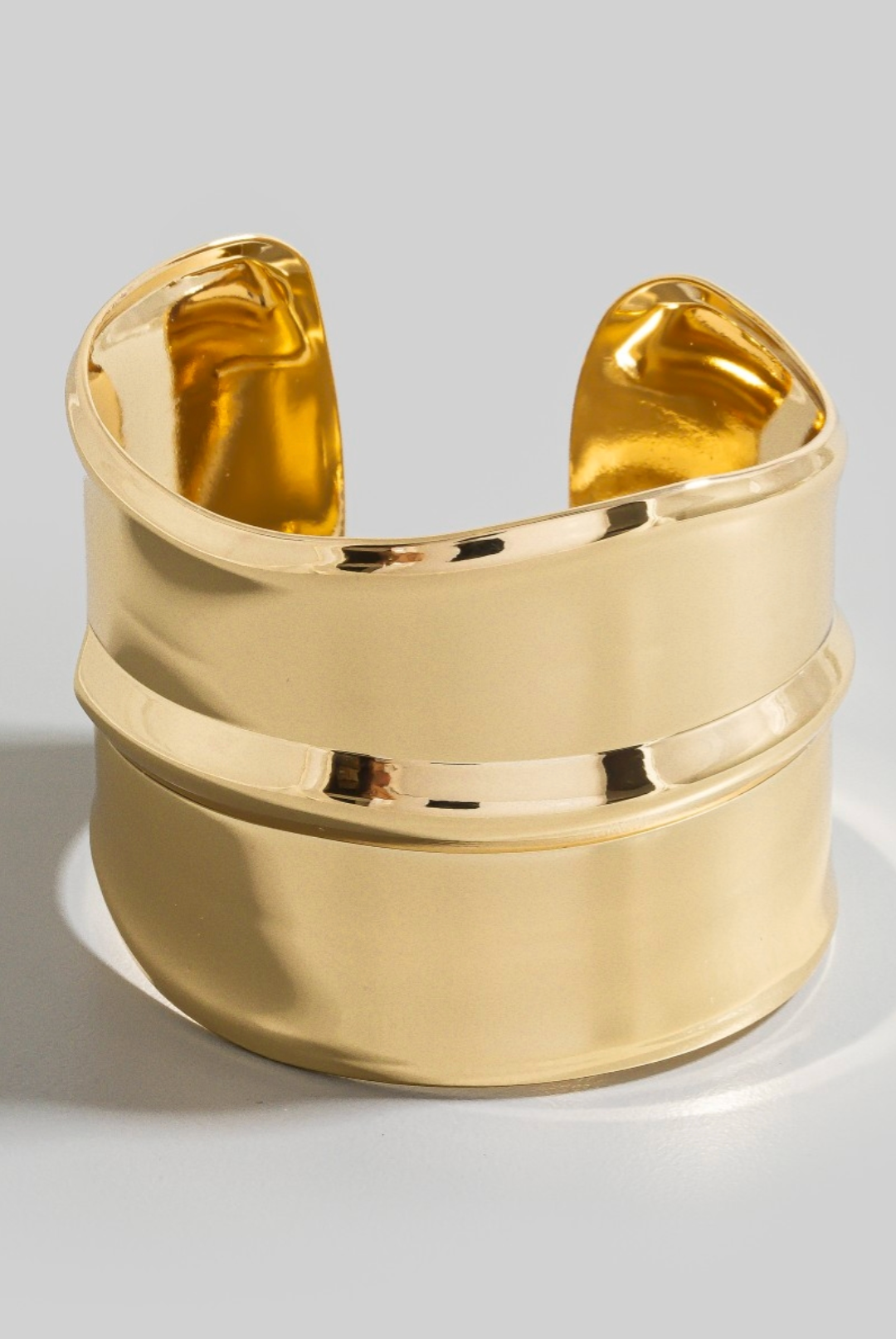 Wide polished gold metallic cuff bracelet with sculptural design and open back
