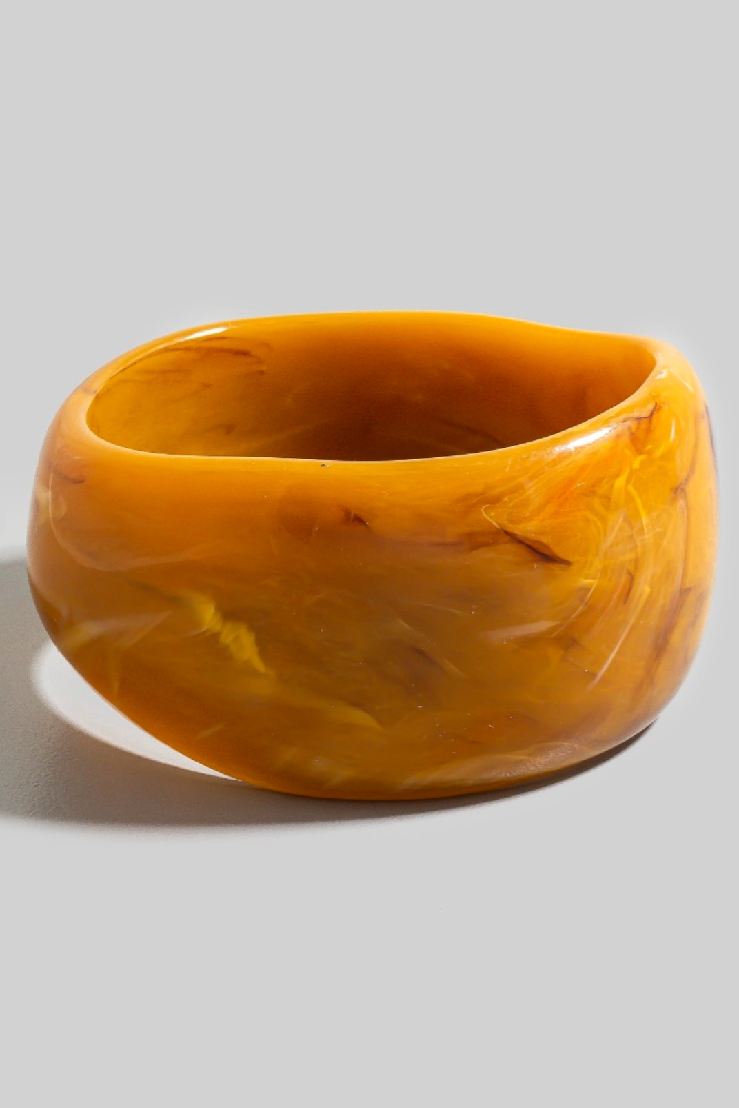 Thick marbled resin bangle bracelet in golden tones with glossy sculptural finish