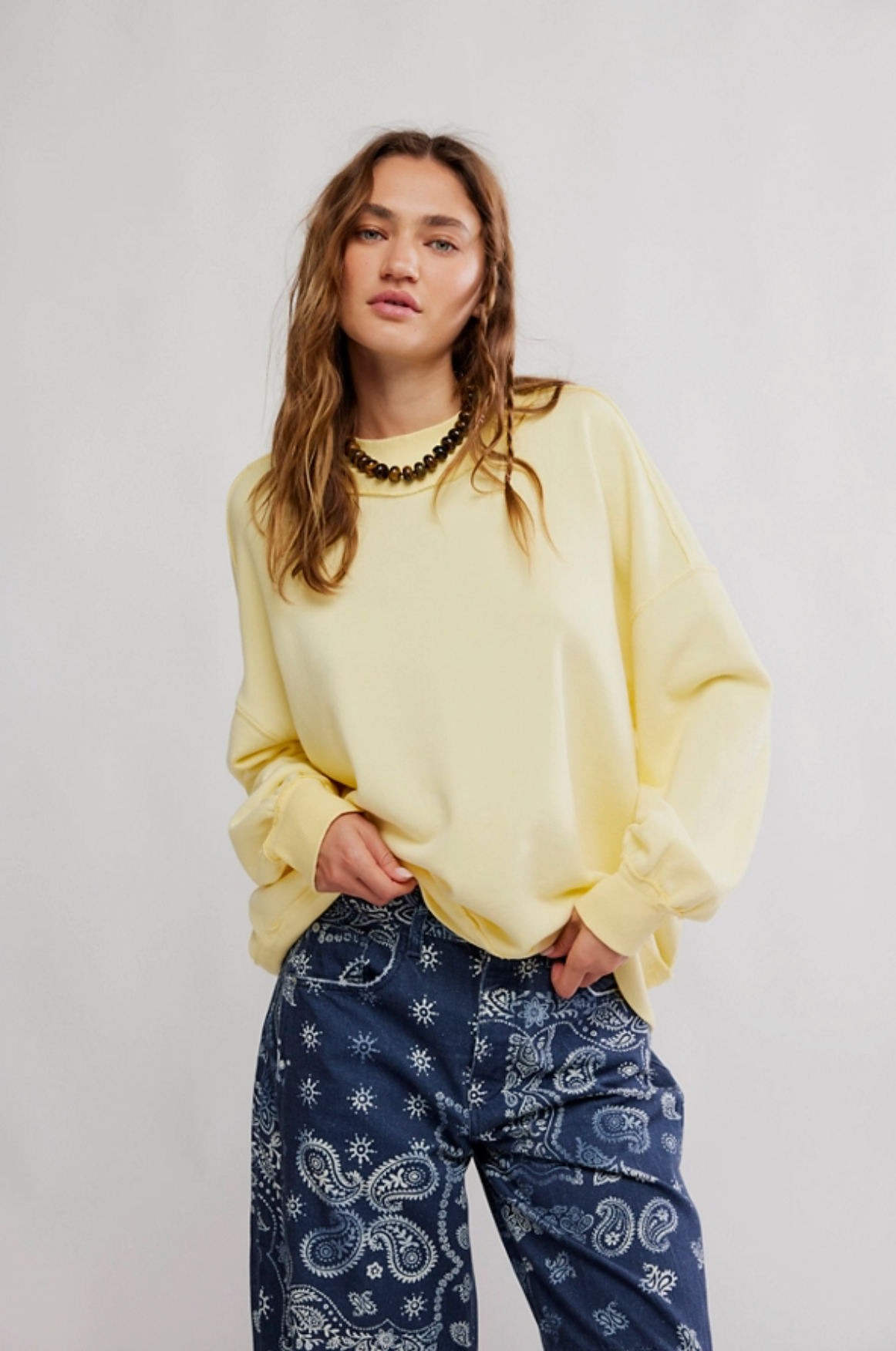 Person wearing a yellow sweater and blue patterned pants on a plain background