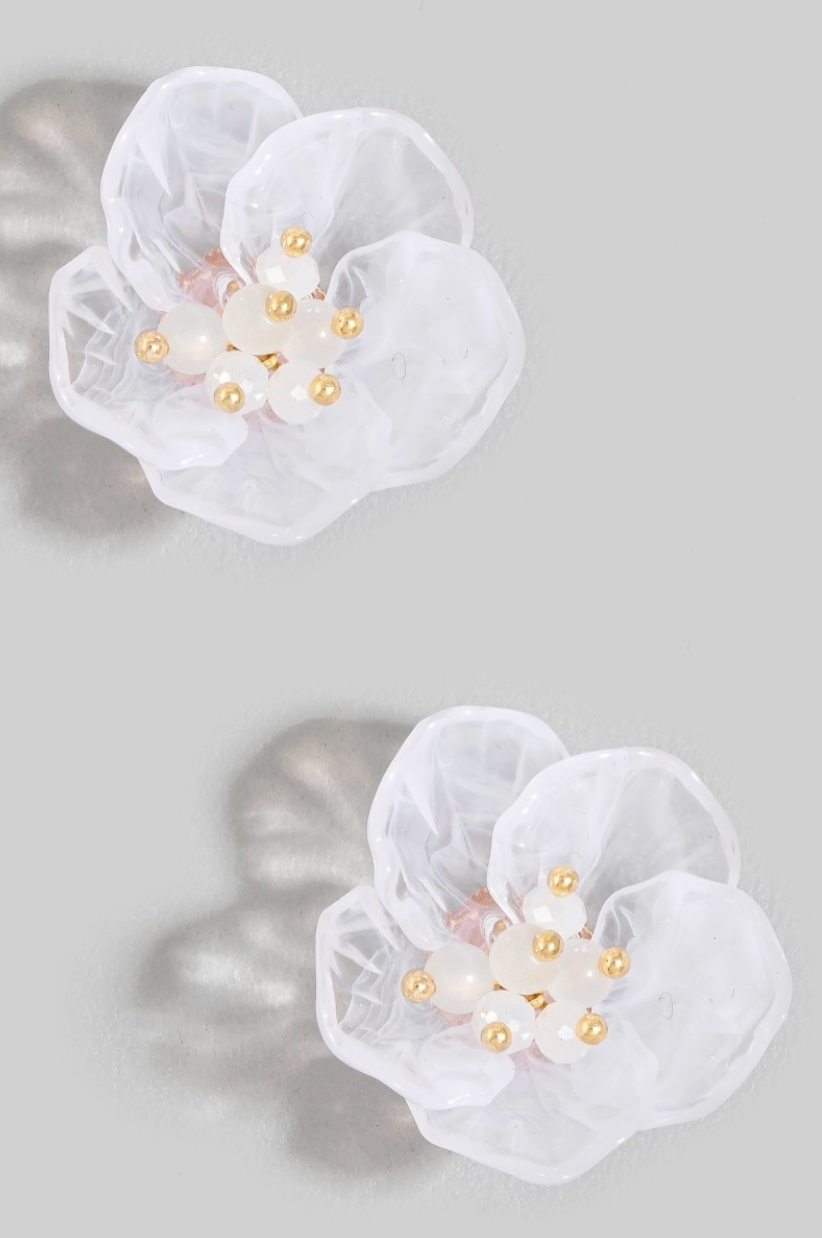 White floral earrings with gold accents on a gray background