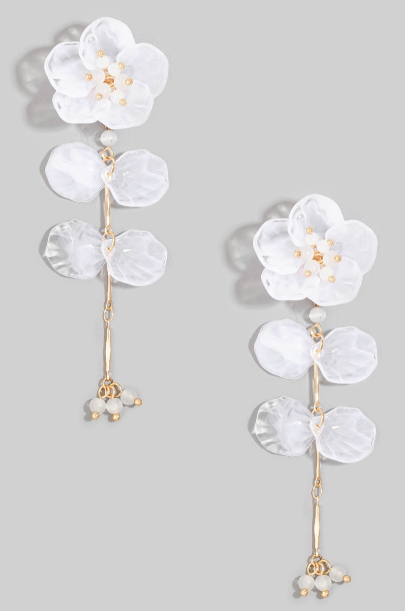 Floral earrings with white petals and gold accents on a gray background