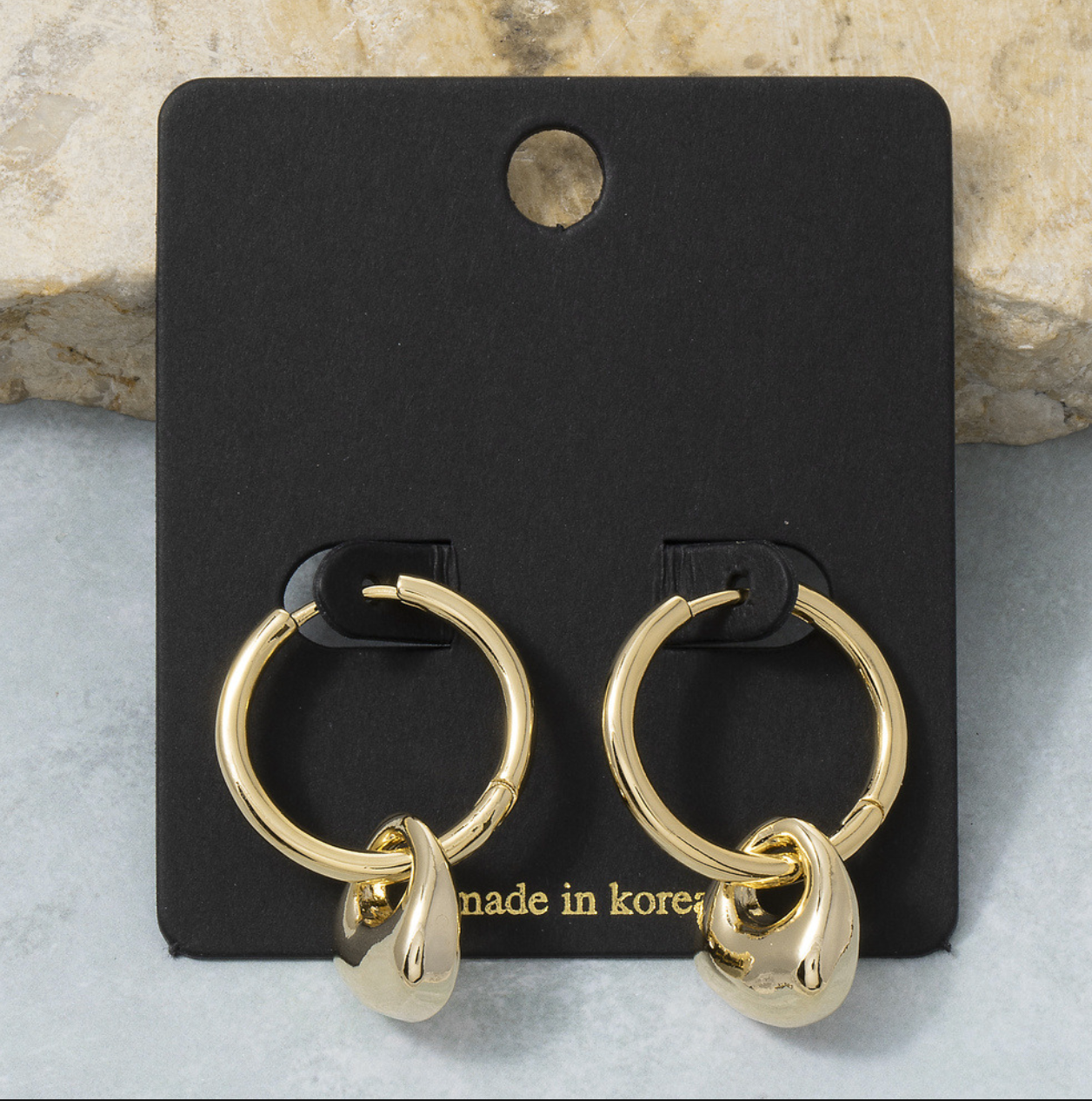 Gold huggie hoop earrings featuring polished dangling teardrop charms.