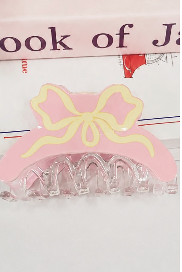 Light pink coquette hair claw clip with cream illustrated ribbon bow and clear resin claw.