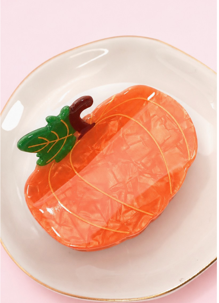Zesty Claw Clip Pumpkin featuring glossy marbled orange acetate with golden detailing, green leaves and a brown stem.