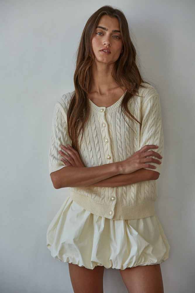 Woman wearing ivory bubble hem mini skort with slouchy socks and black ballet flats