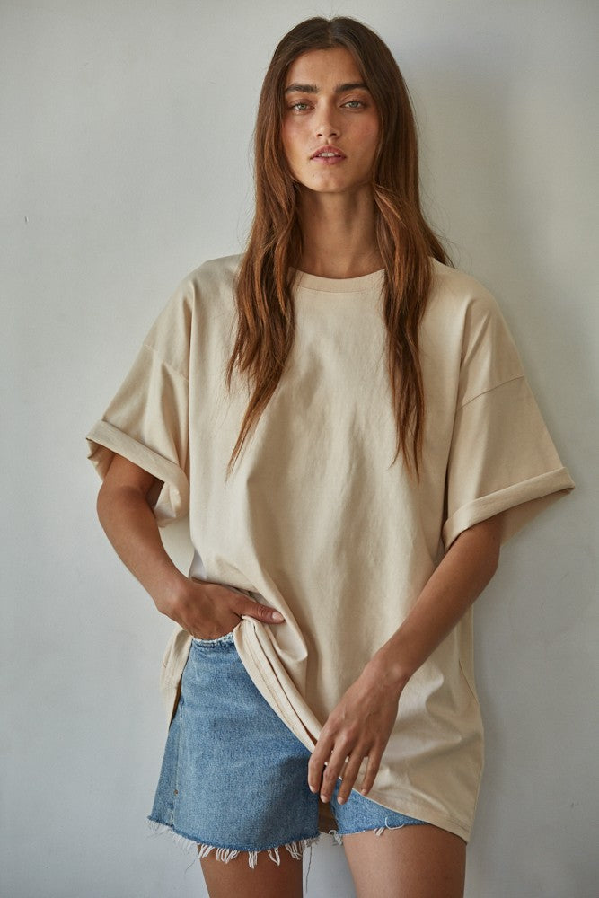 Woman wearing beige oversized cotton tee with drop shoulders and rolled cuffs, paired with a light wash denim mini skirt