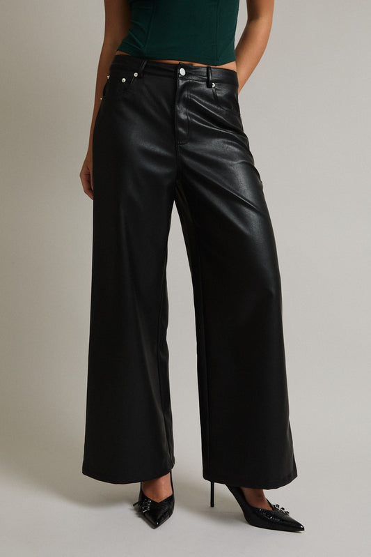 Model wearing high-waisted black faux leather wide-leg pants with back pocket detail