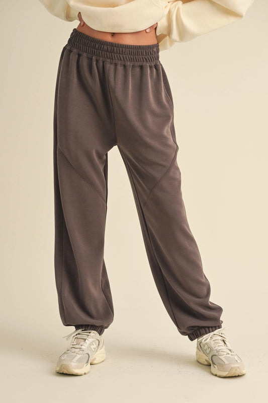 Woman wearing brown low-rise air scuba joggers with elastic cuffs and side pockets.