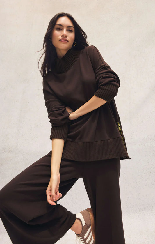 Woman wearing brown mock neck knit top with ribbed trim and side zips