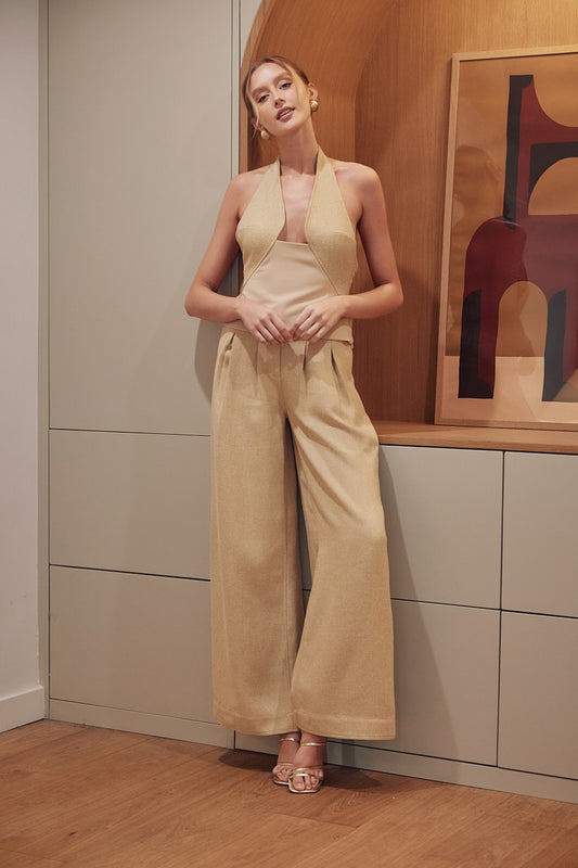 Model wearing gold textured wide-leg pleated trousers with full-length tailored hem