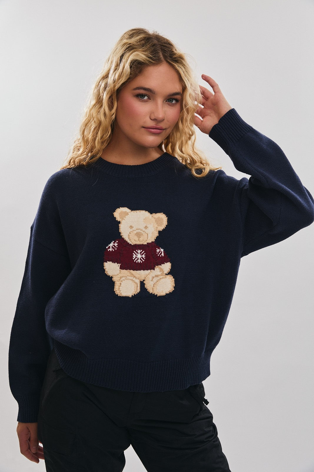Model wearing navy crewneck sweater with teddy bear graphic and relaxed fit