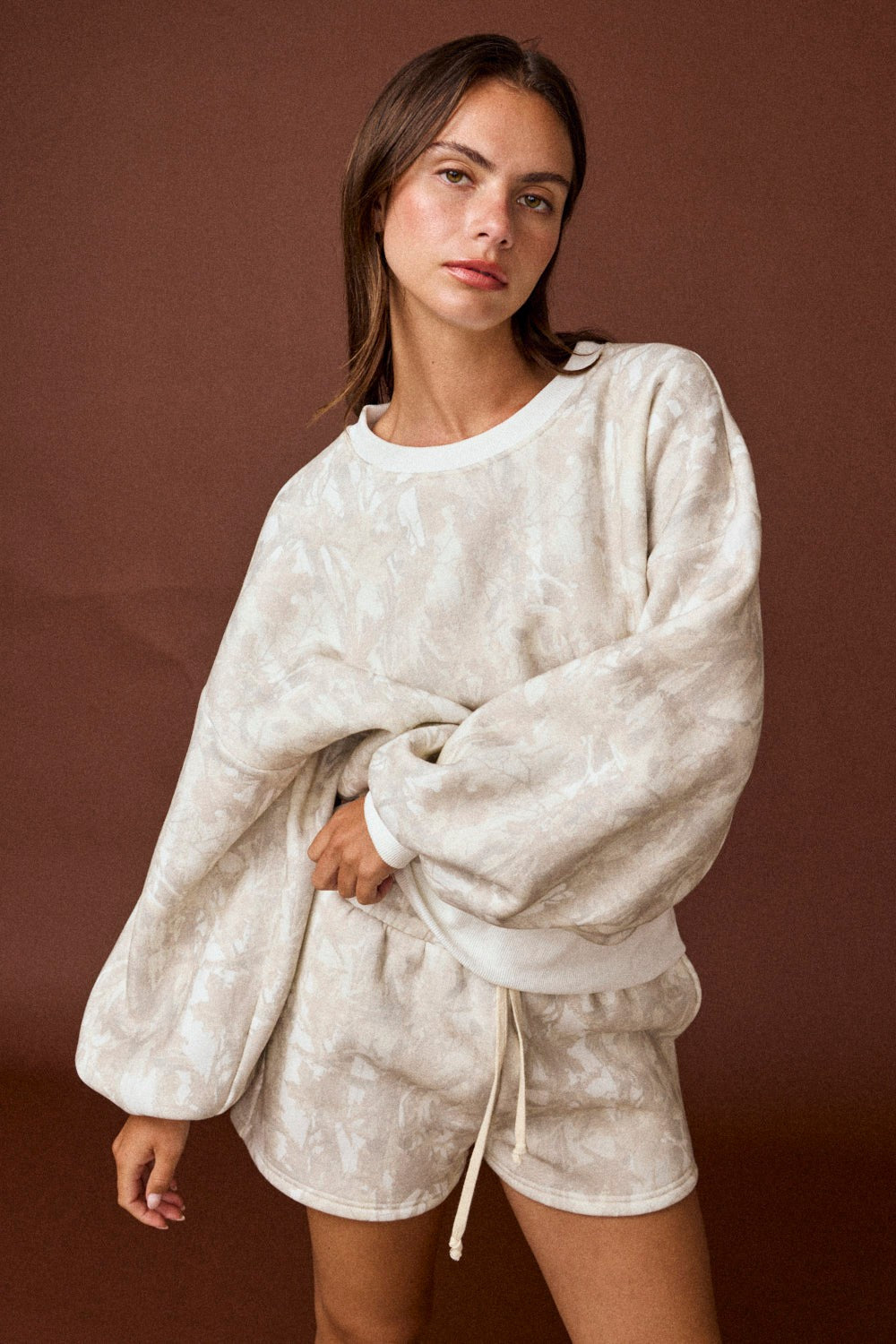 Model wearing oversized tonal camo crewneck sweatshirt with matching high-waisted drawstring shorts.