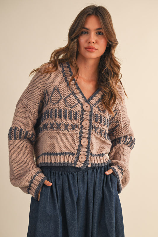 Woman wearing a patterned cardigan with a neutral background