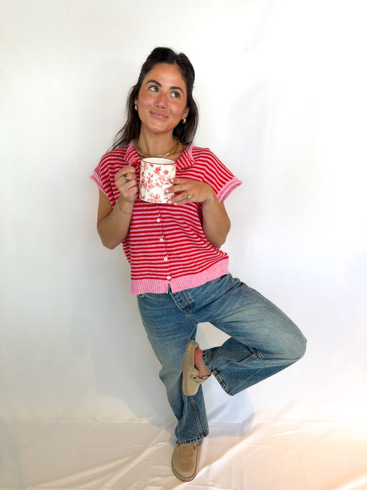 Woman in a red and white striped shirt holding a mug against a plain background