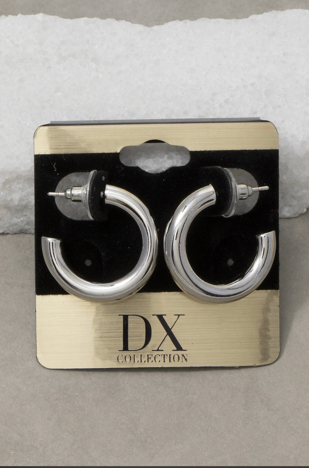 Polished silver thick tube hoop earrings with a smooth mirror finish and oversized silhouette displayed on a jewelry card