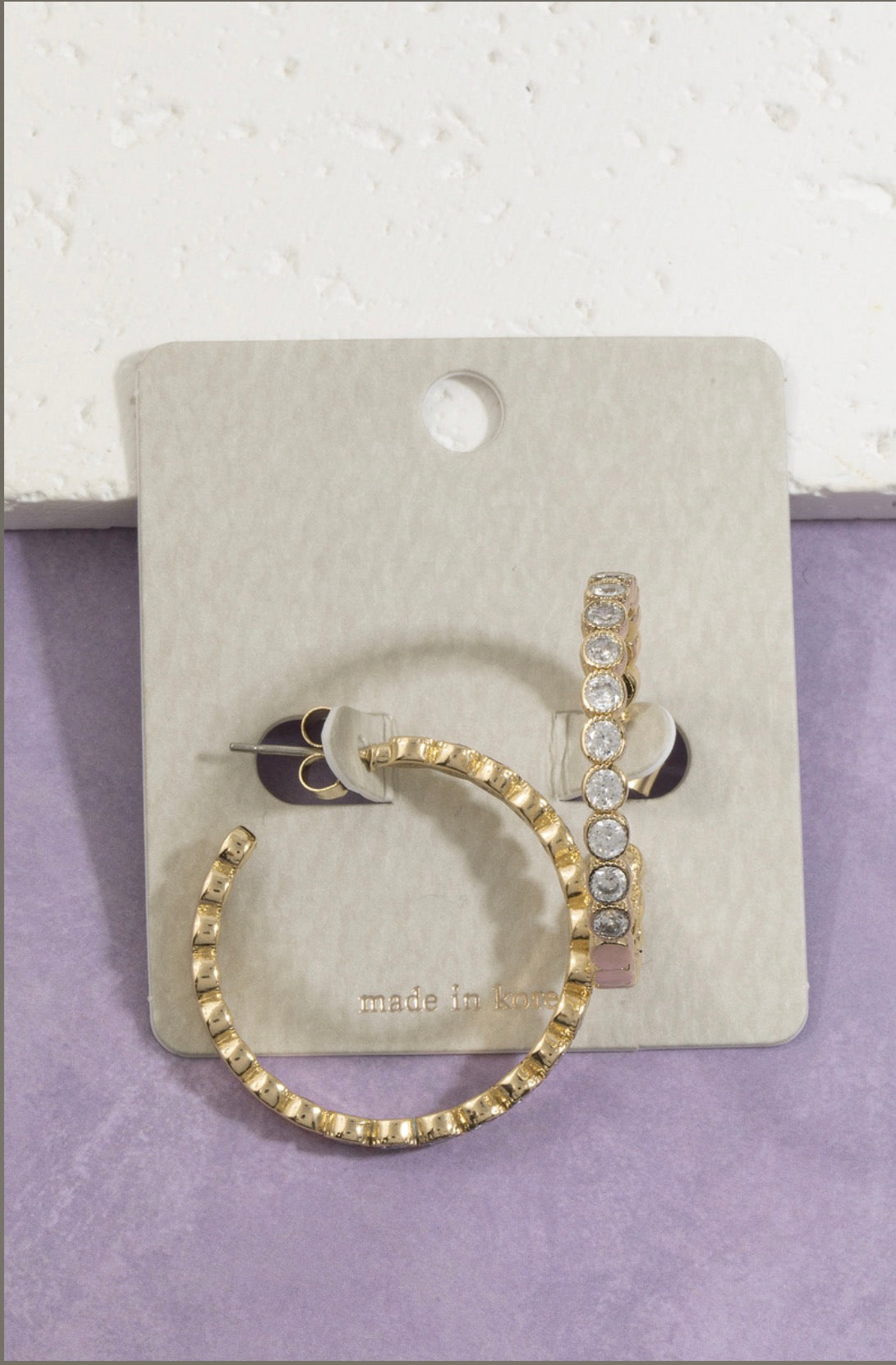 Gold hoop earrings featuring bezel-set round cubic zirconia stones with a lightly textured outer edge, perfect for everyday wear and special occasions.
