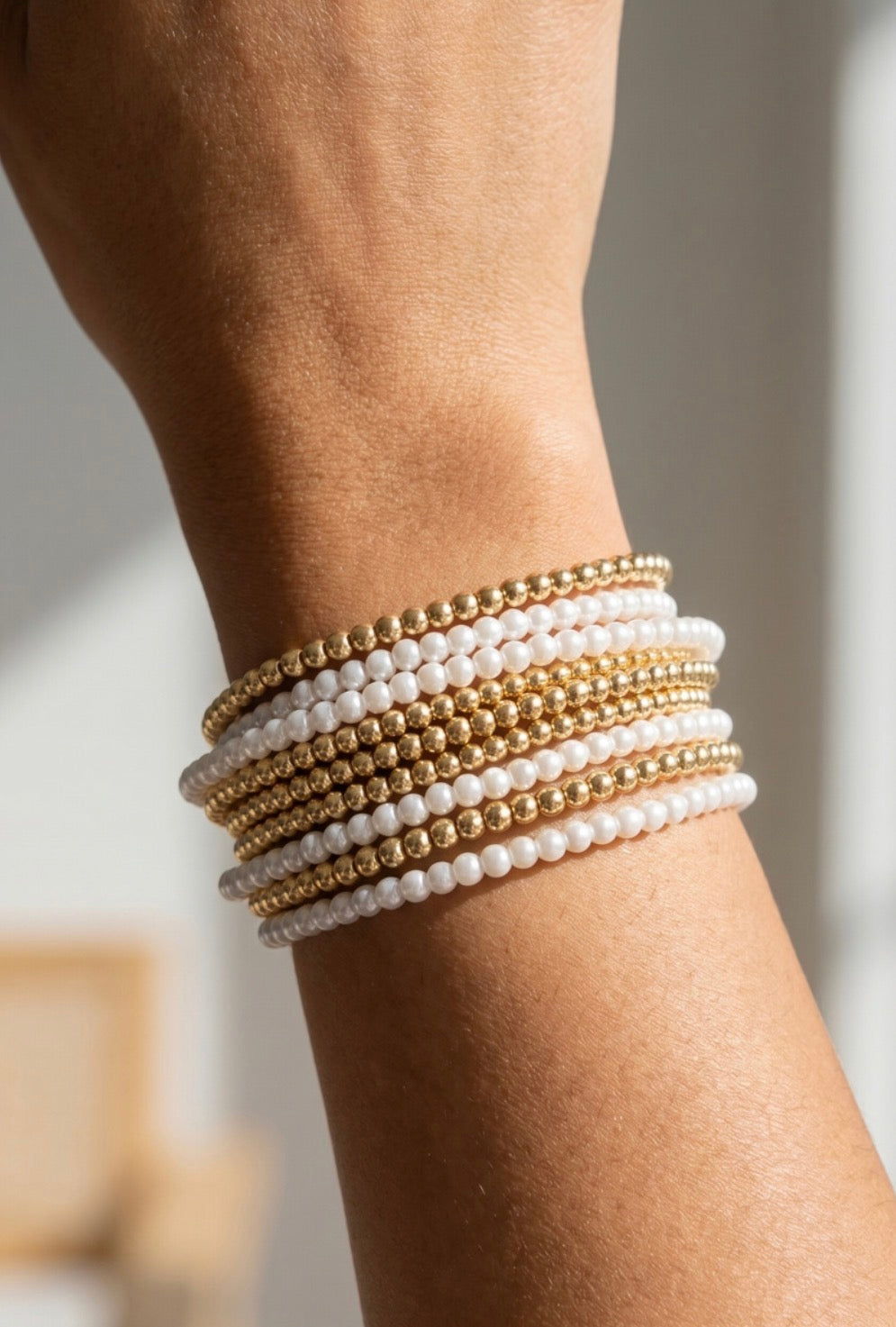 Layered stretch bracelet set featuring pearl-tone and gold-tone beaded strands for an elegant stacked bracelet look.