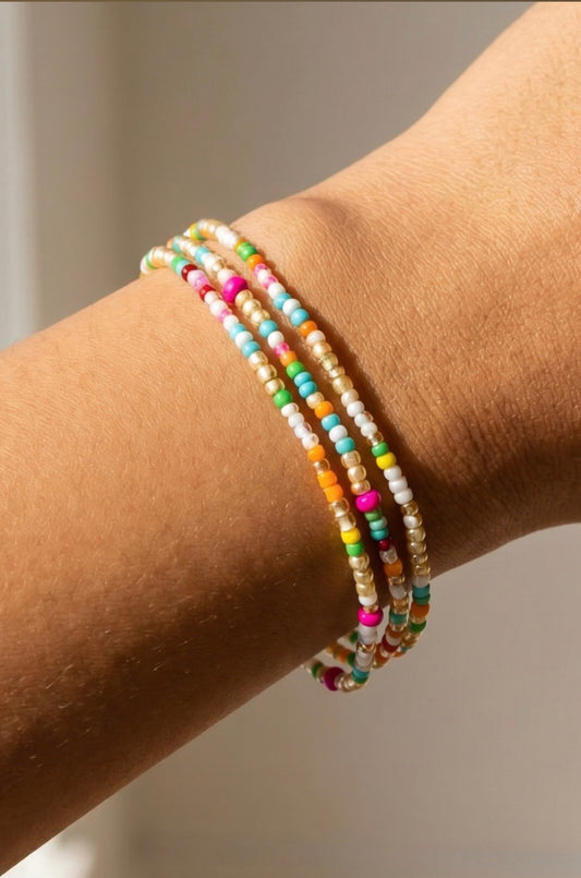 Three-piece multicolor beaded stretch bracelet set featuring colorful seed beads and gold bead accents in a layered stack design.

