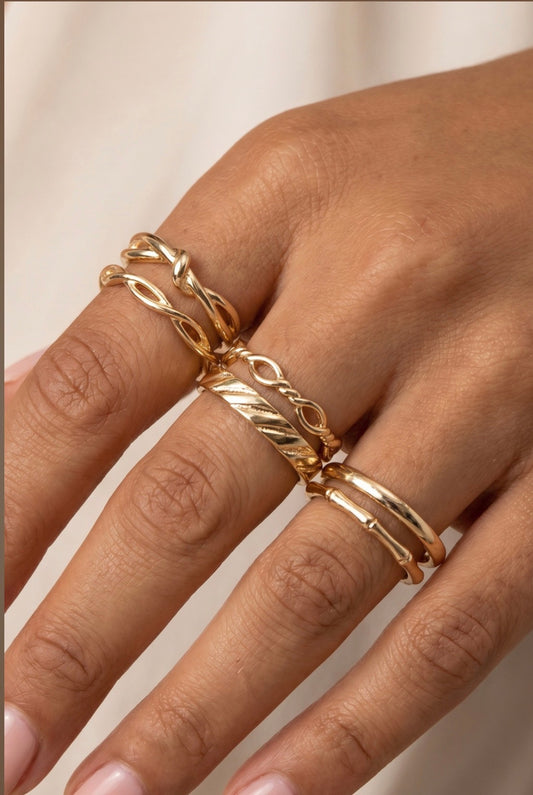 Five-piece gold textured ring stack featuring twisted, woven, Figaro chain, dome, and engraved bands for a layered everyday look.