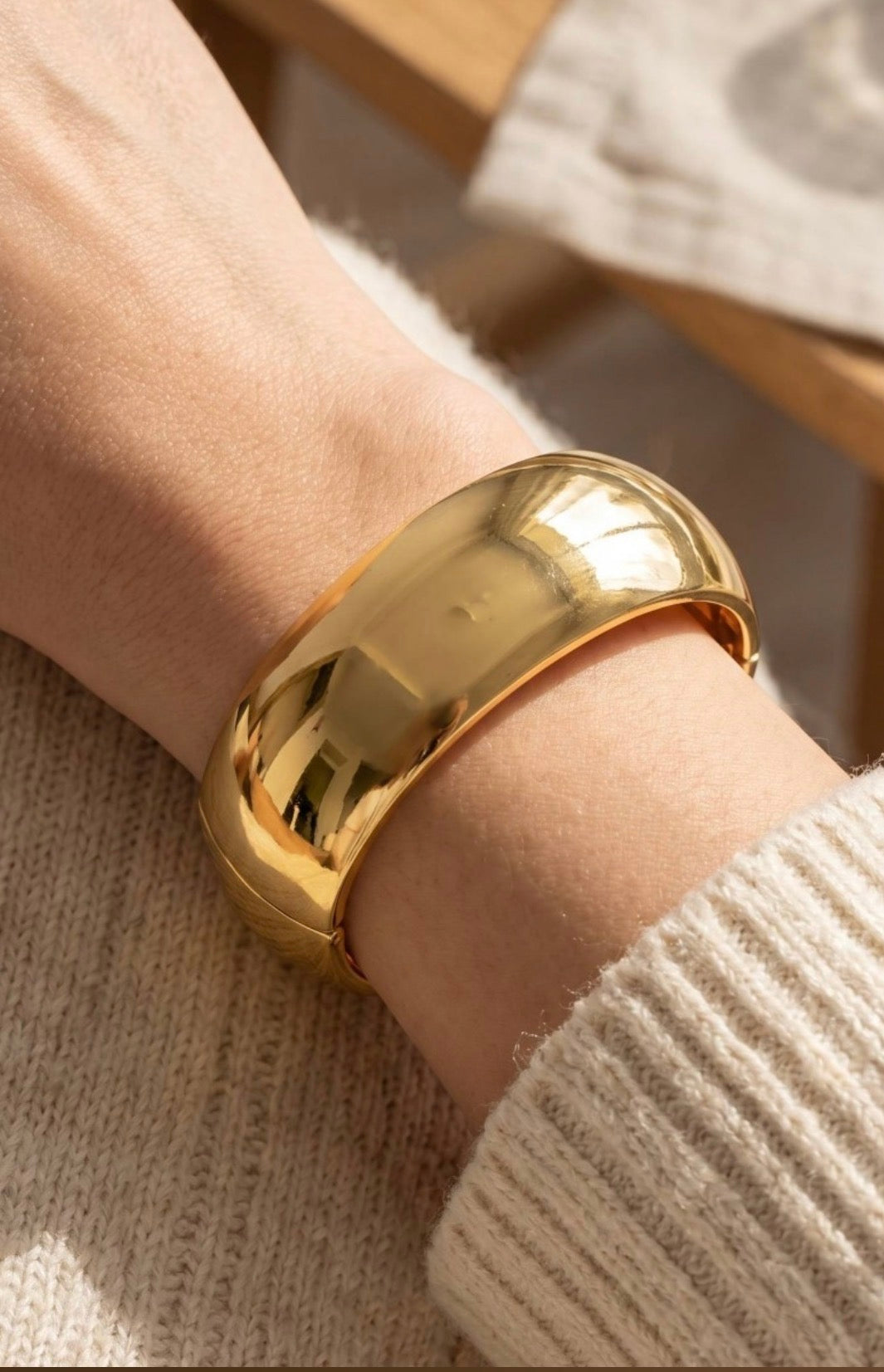 Wide gold dome bangle bracelet with a smooth polished finish and hinged closure for a bold, modern statement look.