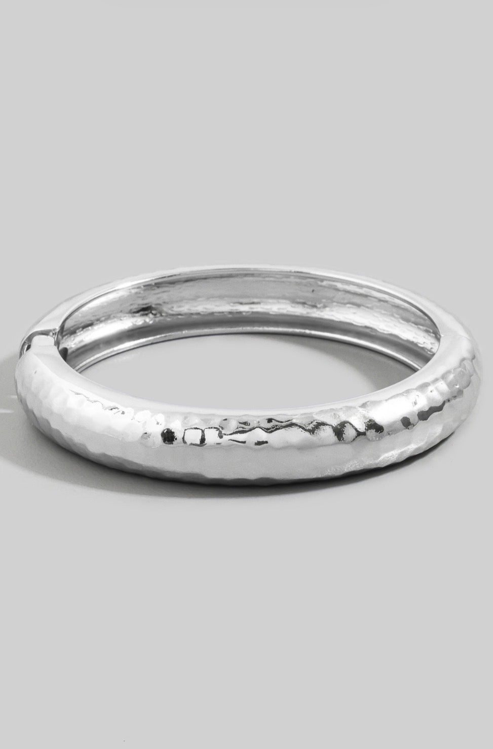 Hammered dome bangle bracelet with a polished textured finish and hinged closure.