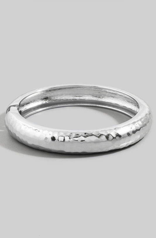 Hammered dome bangle bracelet with a polished textured finish and hinged closure.