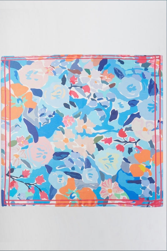Square blue floral bandana scarf featuring an abstract garden print in shades of blue, coral, pink, ivory, and navy with a contrasting pink border.