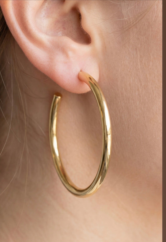 Large polished stainless steel open hoop earrings with a smooth tubular design worn on the ear.