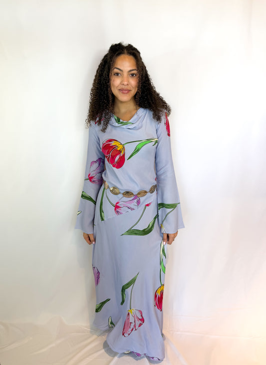 Woman wearing a light blue dress with floral patterns against a white background