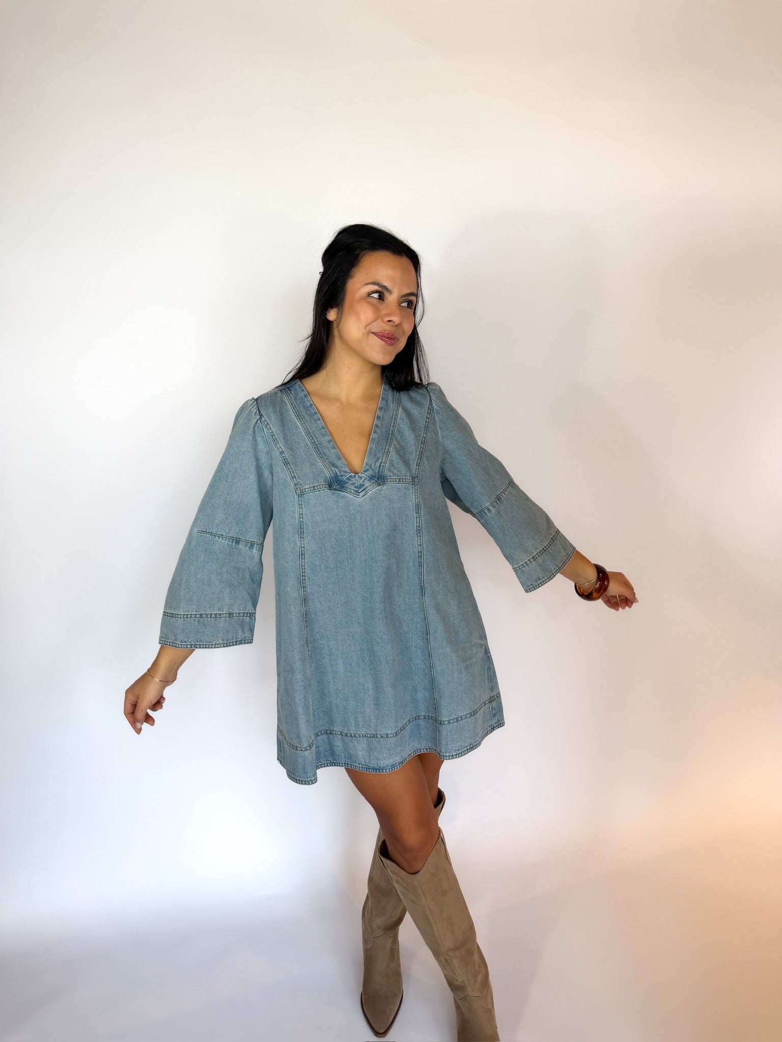 Woman wearing a denim dress with long sleeves on a white background