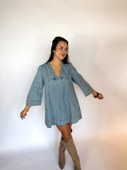 Woman wearing a denim dress with long sleeves on a white background