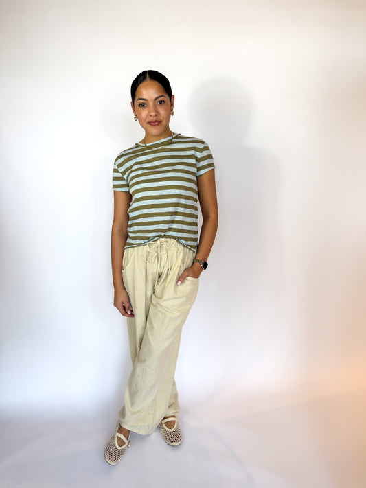 Person wearing a green and white striped shirt with beige pants on a plain background