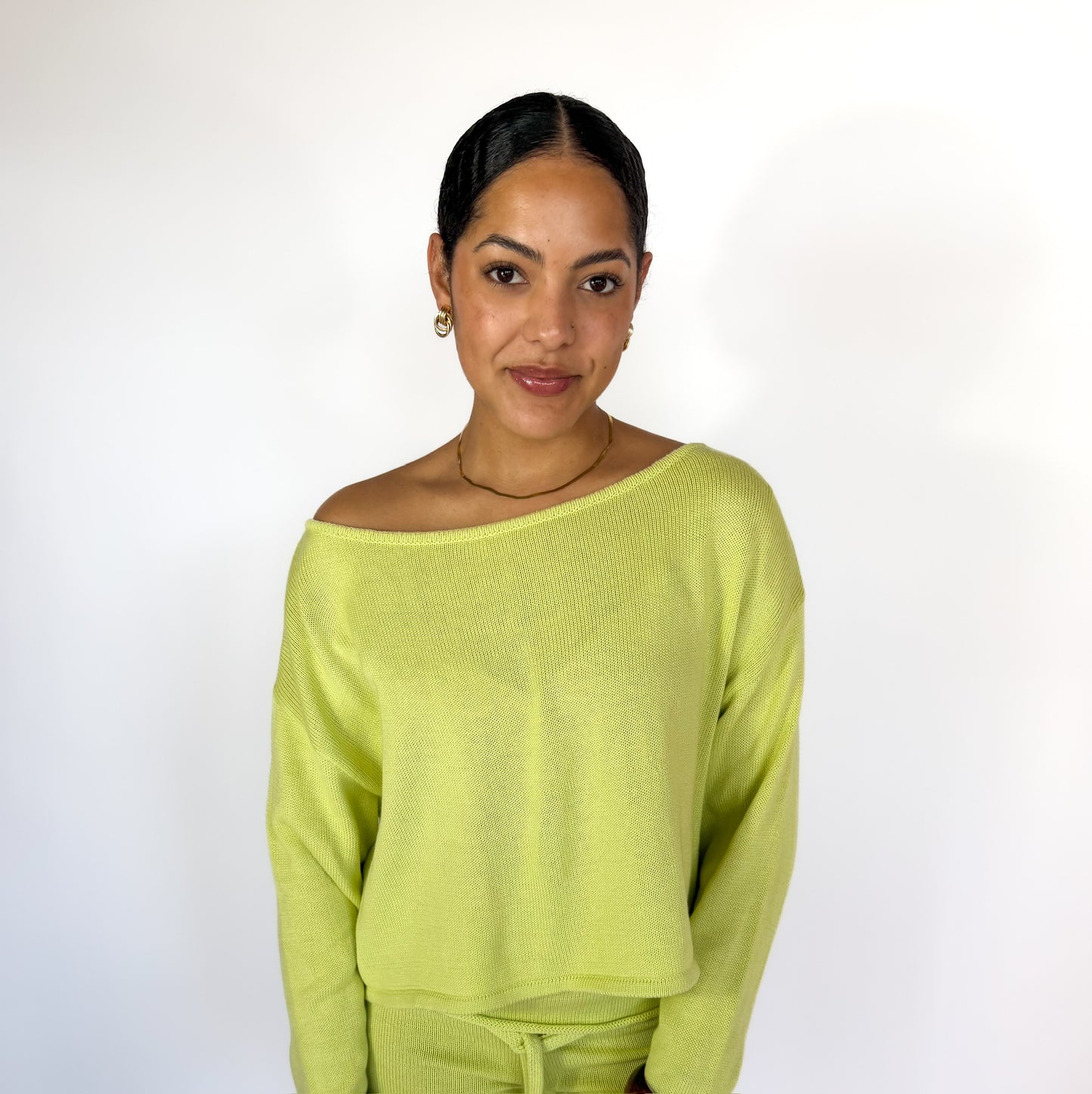 Woman wearing a light green sweater against a white background
