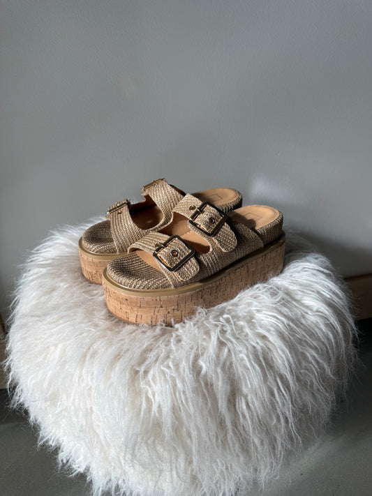 Wooden sandal with a fluffy white rug on a gray background