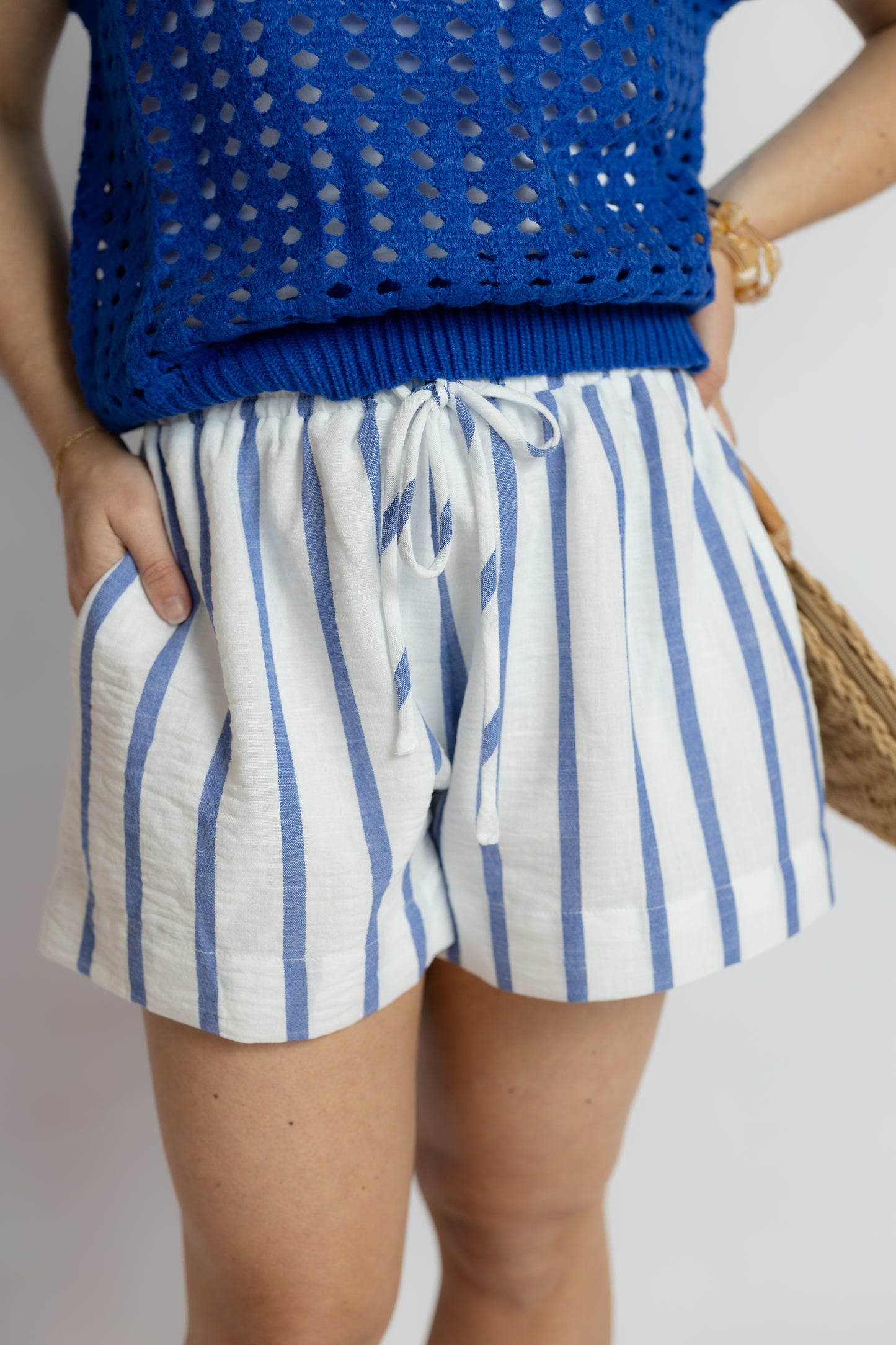 Person wearing blue striped shorts and a blue top on a plain background