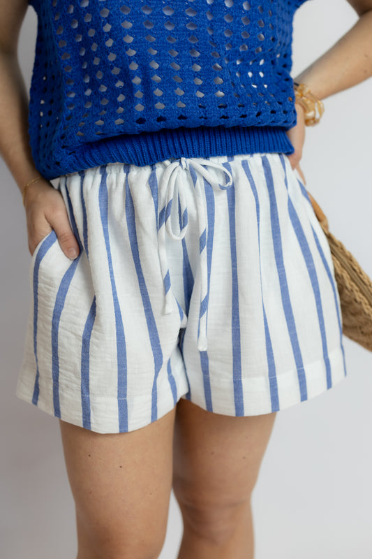 Person wearing blue striped shorts and a blue top on a plain background