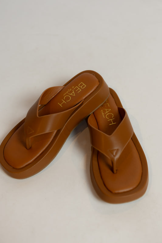 Pair of brown sandals with 'Beach' branding on a light background