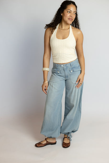 Woman wearing a white tank top and light blue jeans on a plain background