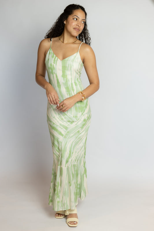 Woman wearing a green and white patterned dress on a plain background