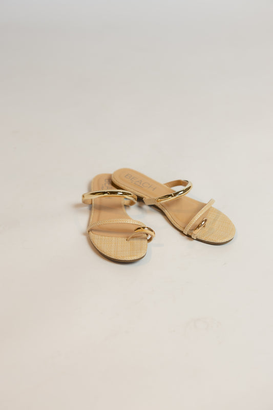Pair of gold sandals on a light beige background