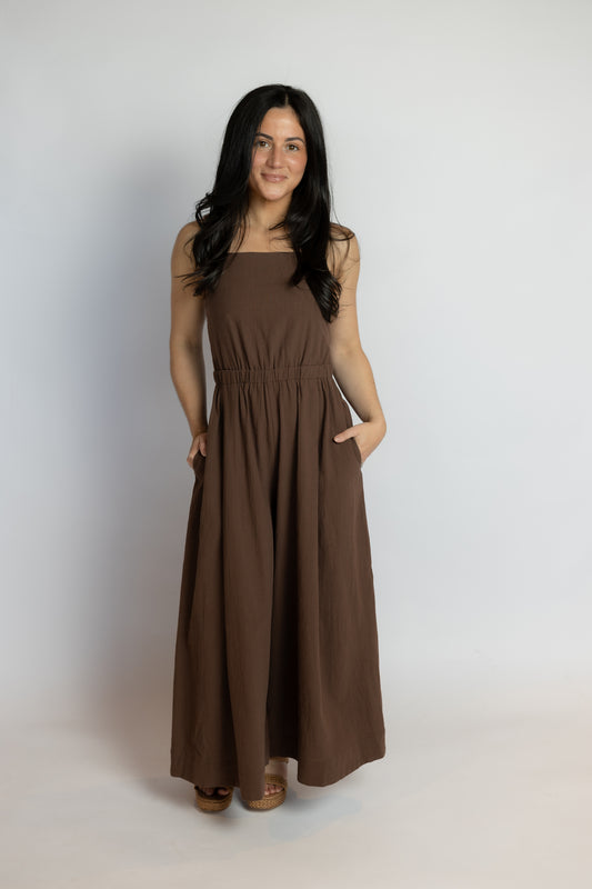 Woman wearing a brown sleeveless dress against a white background