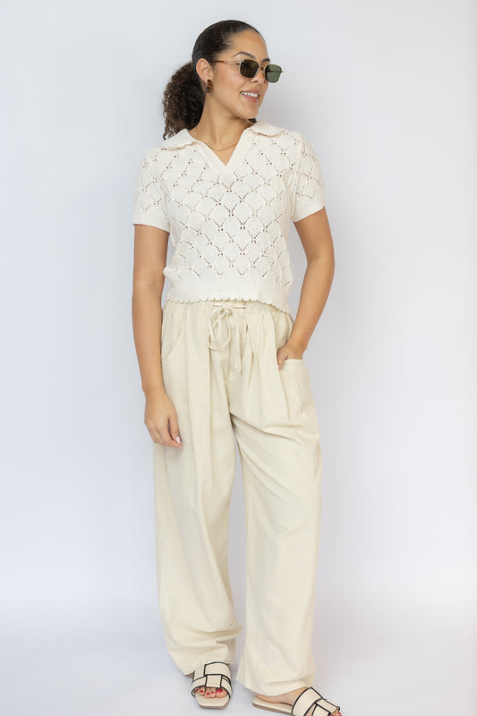 Woman wearing a white textured top and beige pants against a white background