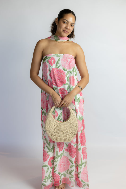 Woman wearing a floral dress holding a woven bag against a white background