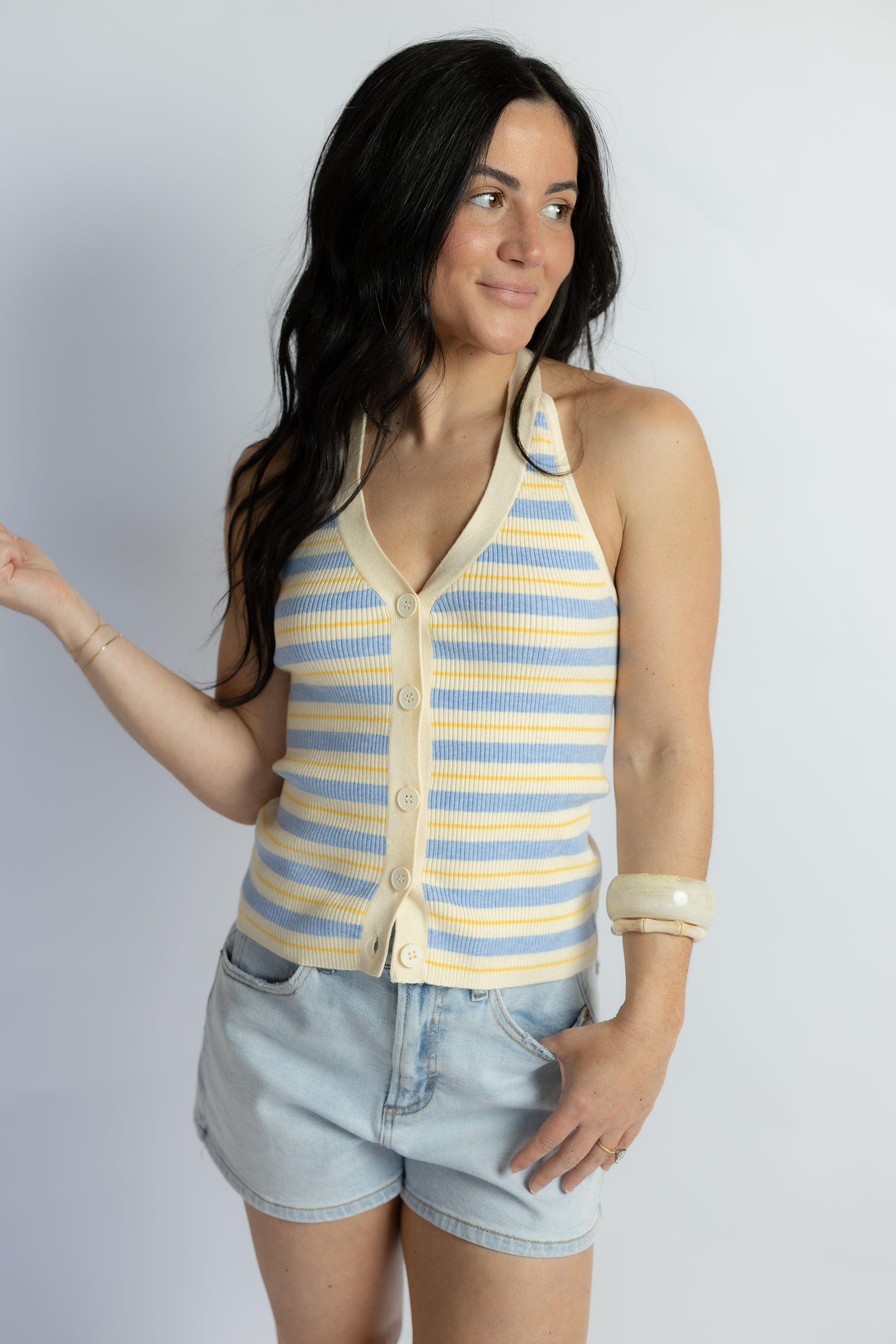 Woman wearing a striped sleeveless top and shorts on a plain background